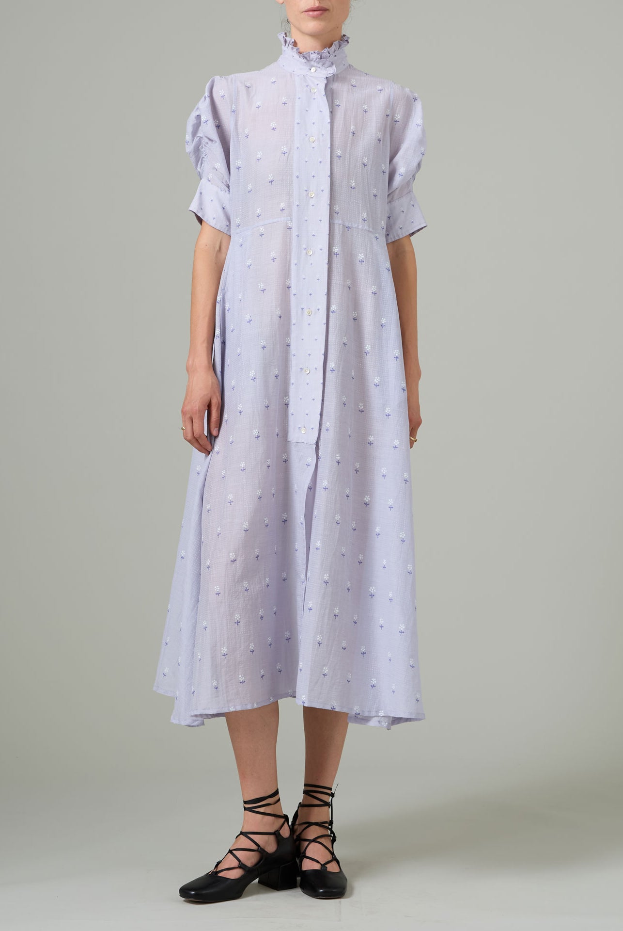 Person wearing a light purple dress with white patterns on a plain background