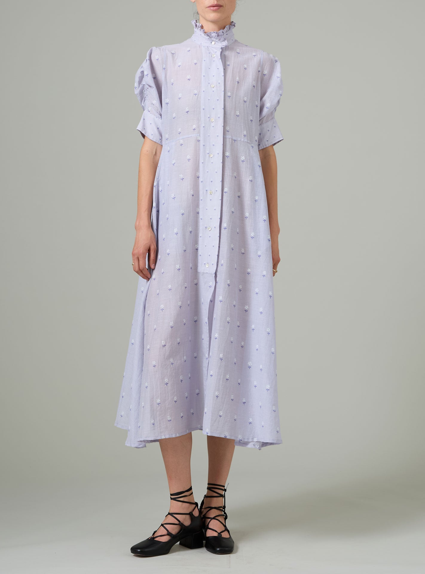 Person wearing a light purple dress with white patterns on a plain background