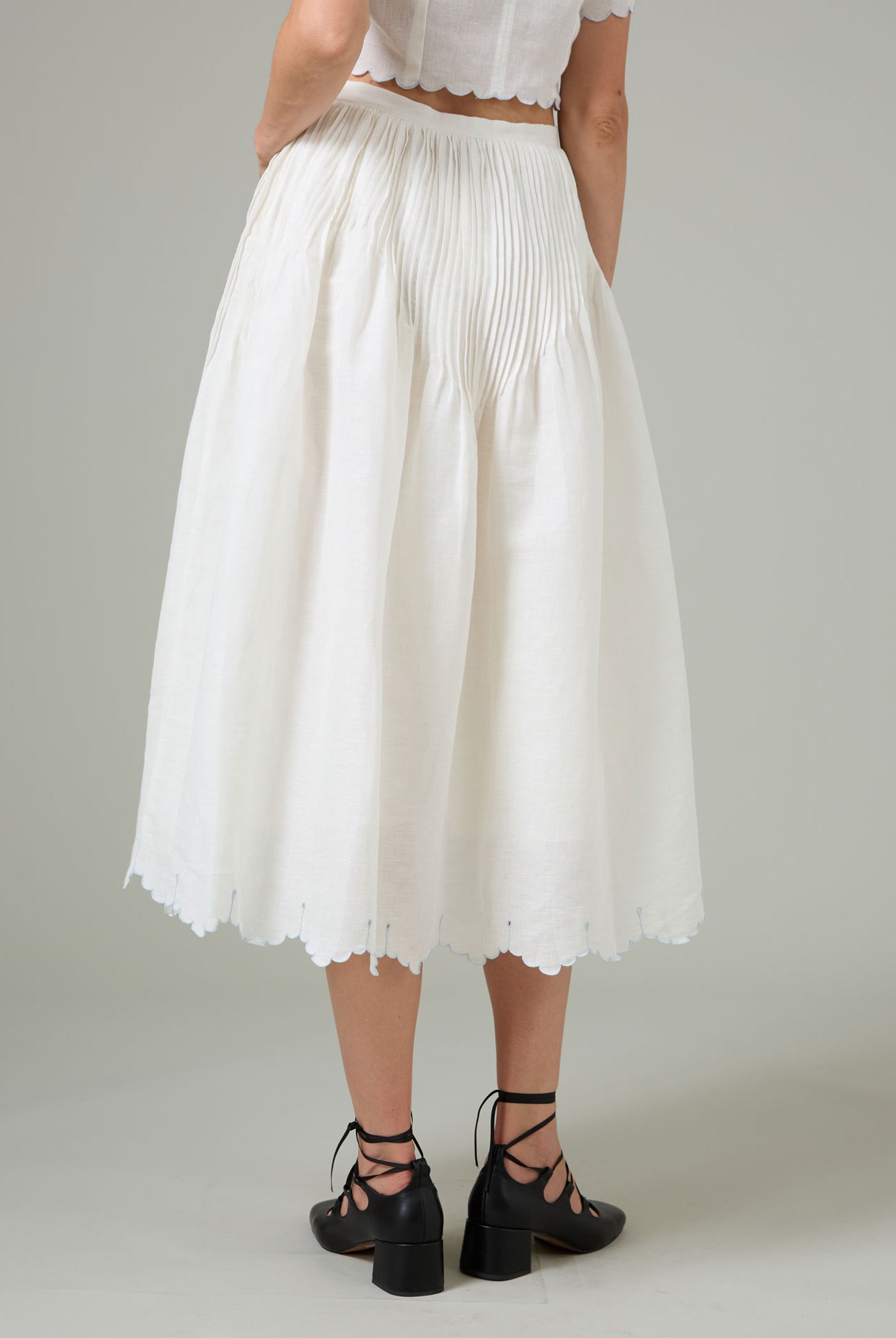 Person wearing a white pleated Verde skirt by thierry Colson on a plain background