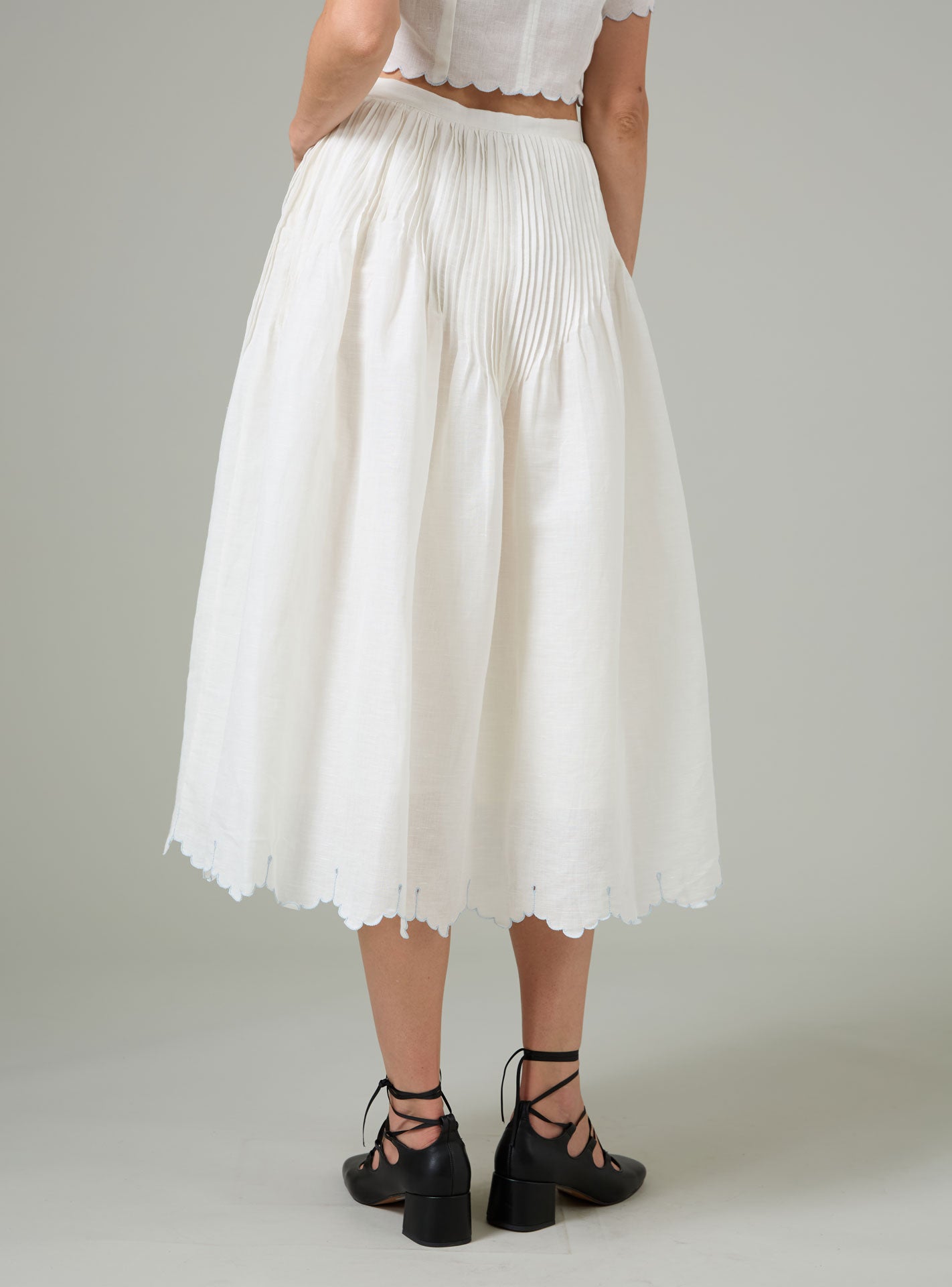 Person wearing a white pleated Verde skirt by thierry Colson on a plain background