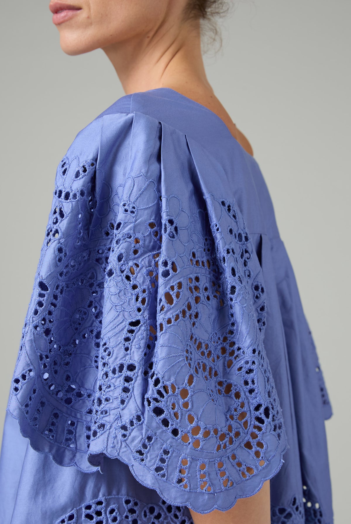Blue lace top worn by a person on a plain background