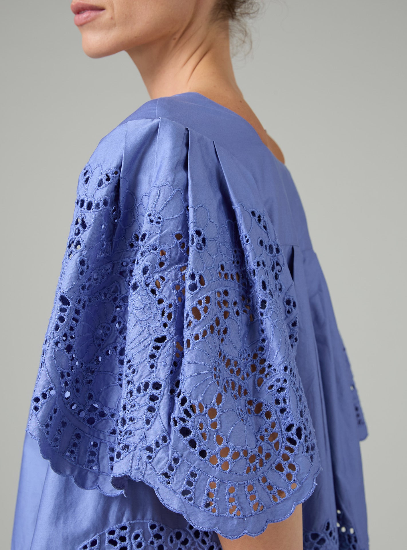 Blue lace top worn by a person on a plain background