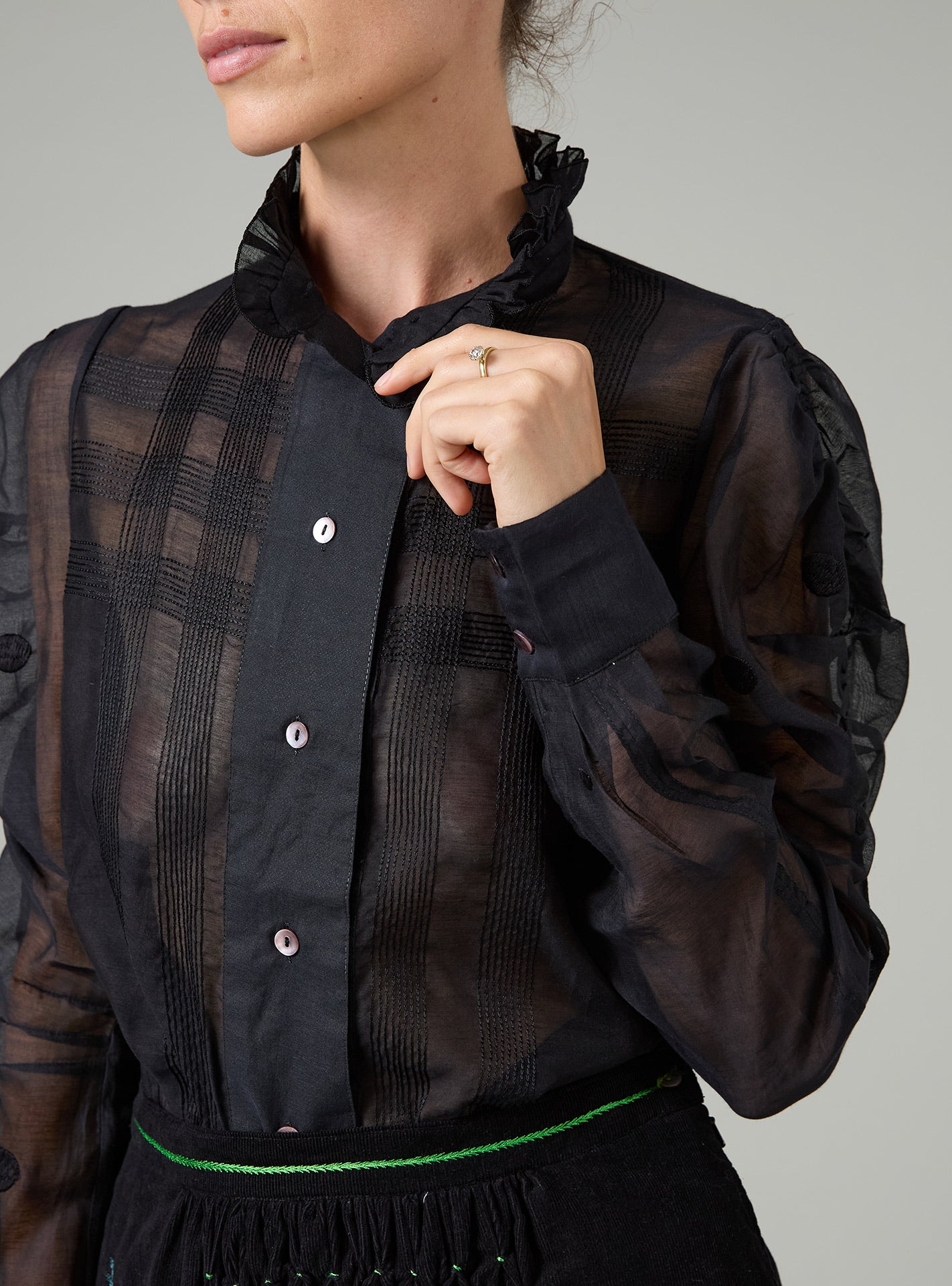 Person wearing a black sheer blouse with a plain background
