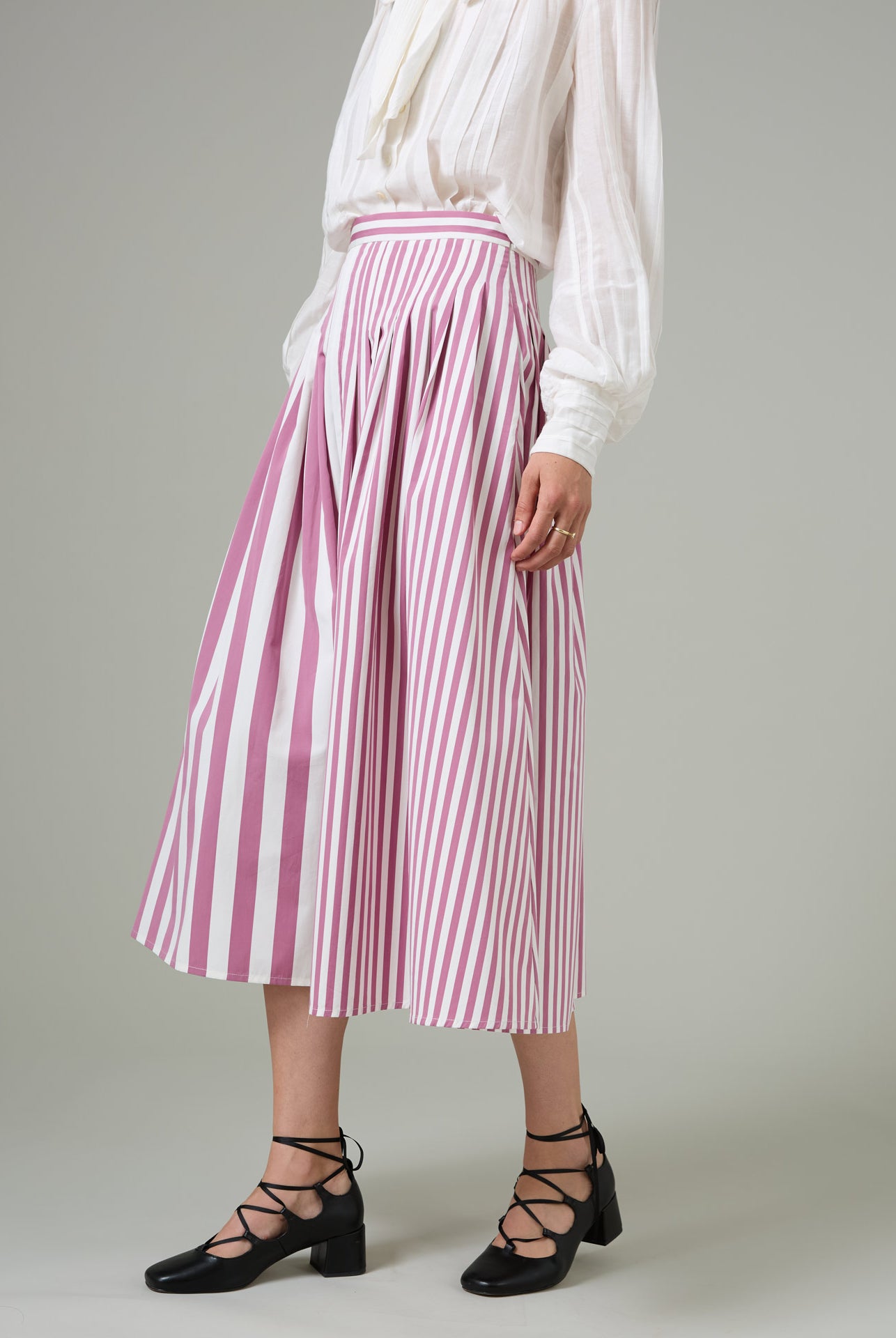 The Zazou skirt in Cyclamen Lido stripes by Thierry Colson, swings with elegance, featuring contrasted stripe panels and engineered darts for a slender, sculpted silhouette.