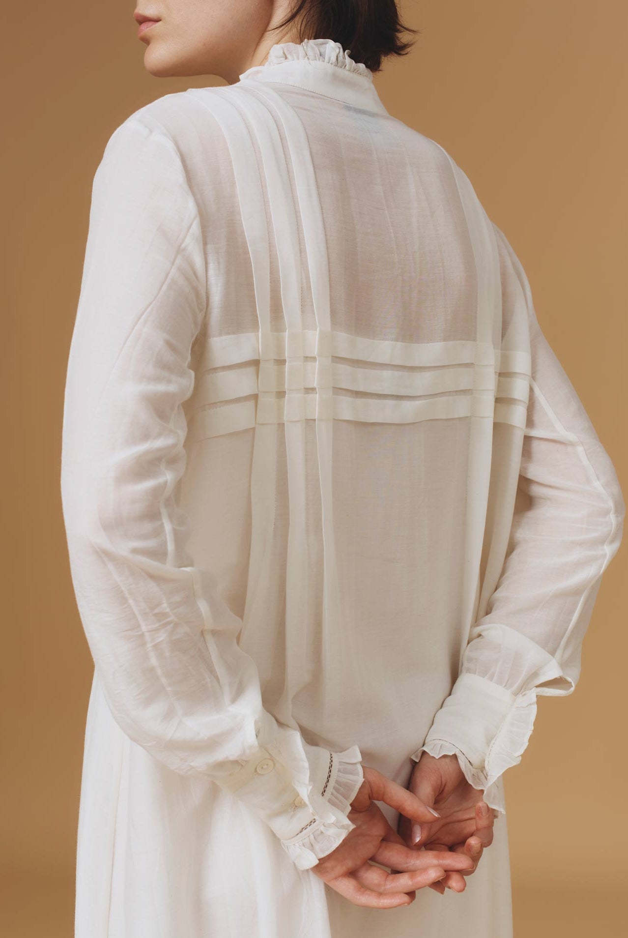 Close up back view of Zita Optical Pleats Off White dress by Thierry Colson