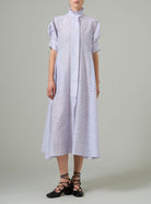 Person wearing a light purple dress with white patterns on a plain background