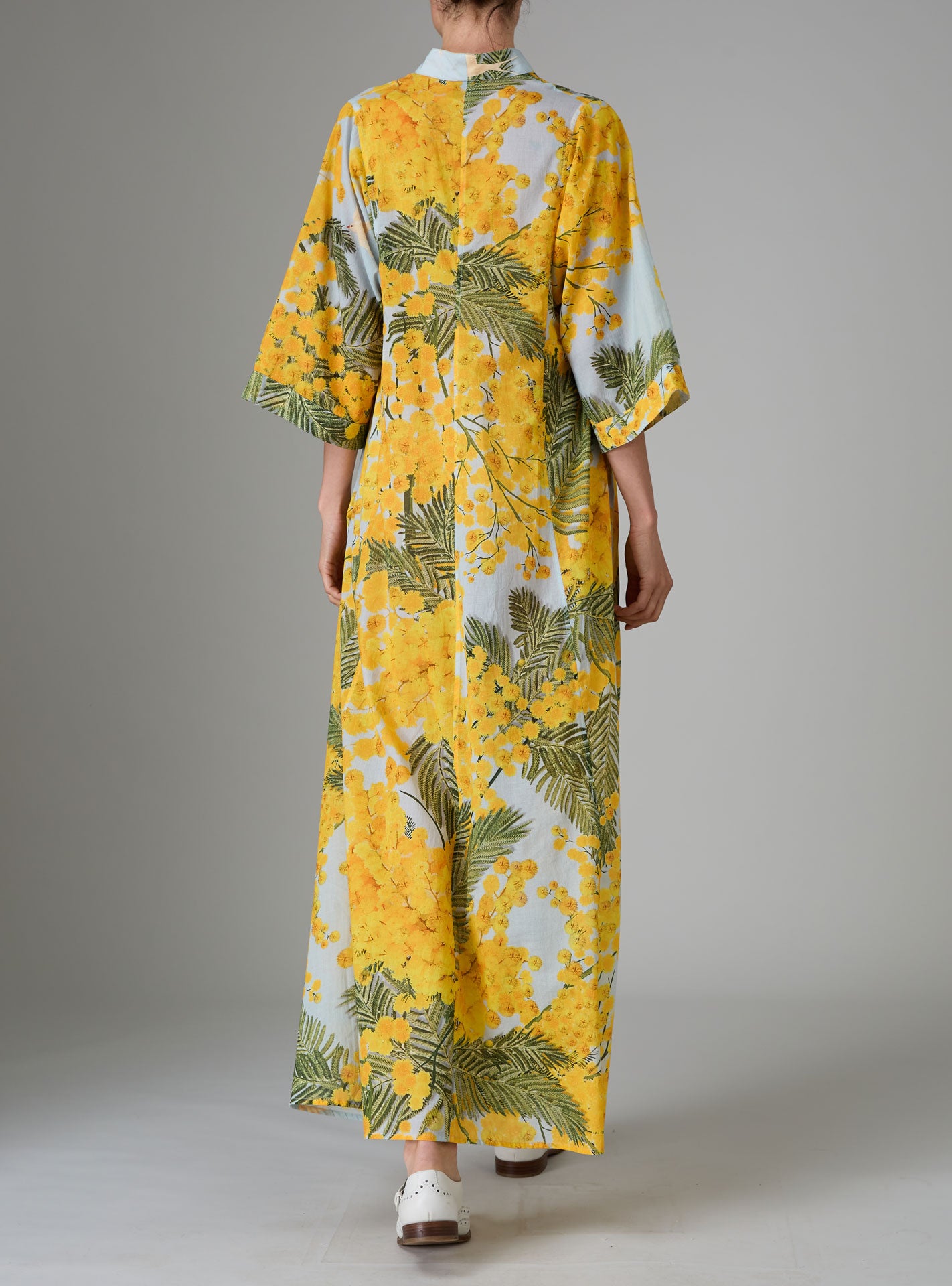 Back view of Rachel Kaftan in yellow and storm blue, featuring pagoda sleeves and high slit, inspired by mimosa gardens of the French Riviera. PS25 collection by Thierry Colson