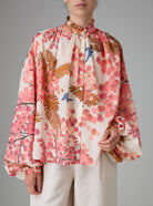 Front view of SLAVA blouse with wide bell sleeves and collar band, crafted in pink and off-white digitally printed cotton voile for Pre-Spring 2025 by Thierry Colson